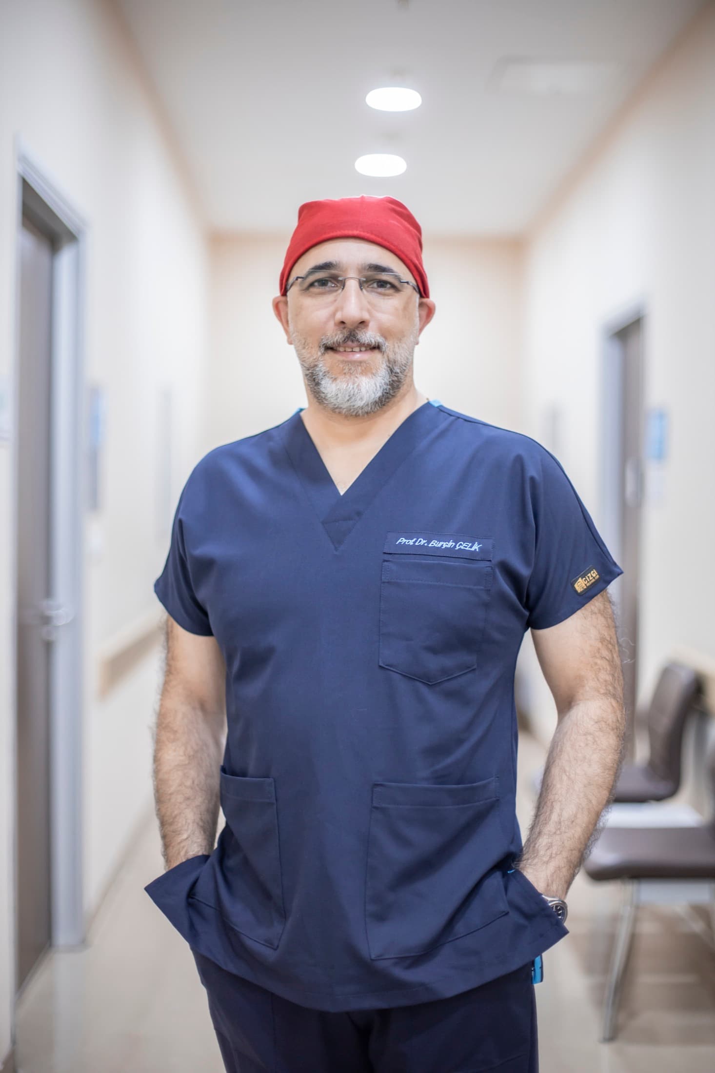 Prof. Dr. Burçin Çelik cerrahi forma ve boneyle hastane koridorunda